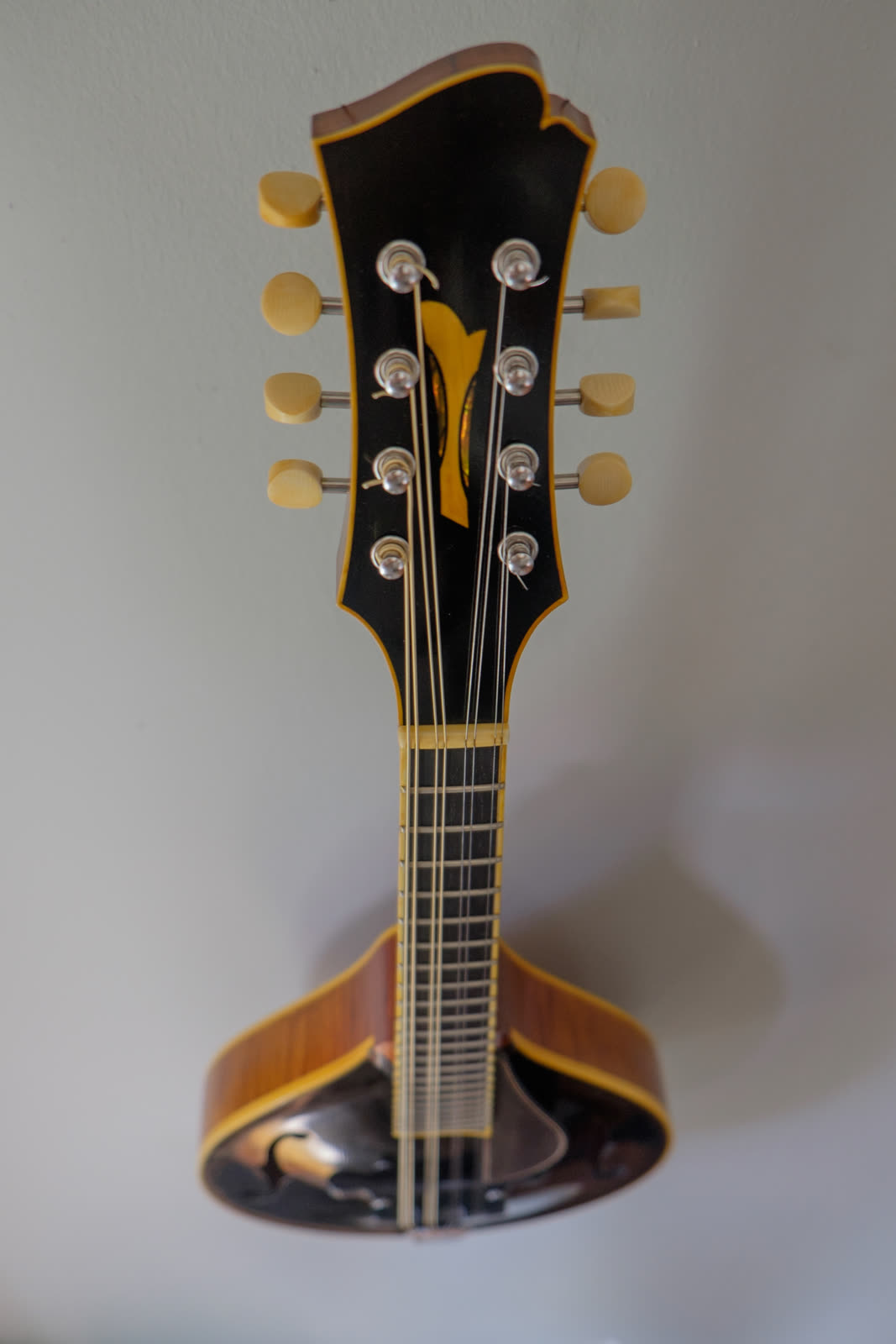 A-model mandolin — peghead, black finish with pearl inlay, amber binding