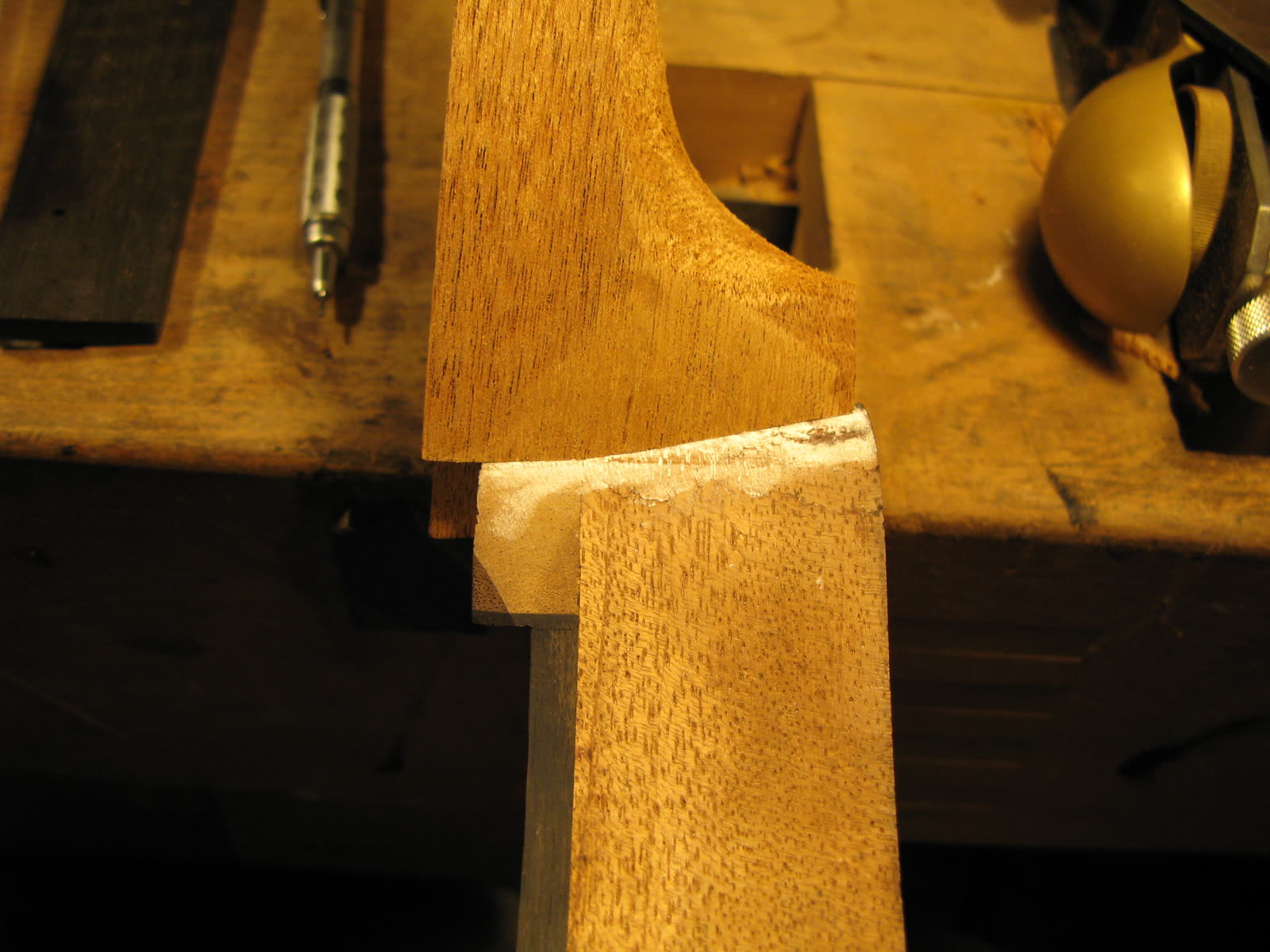 Neck dovetail joint — heel test-fit into the mortise, mahogany, glue smudges show where it was pared for a tighter seat